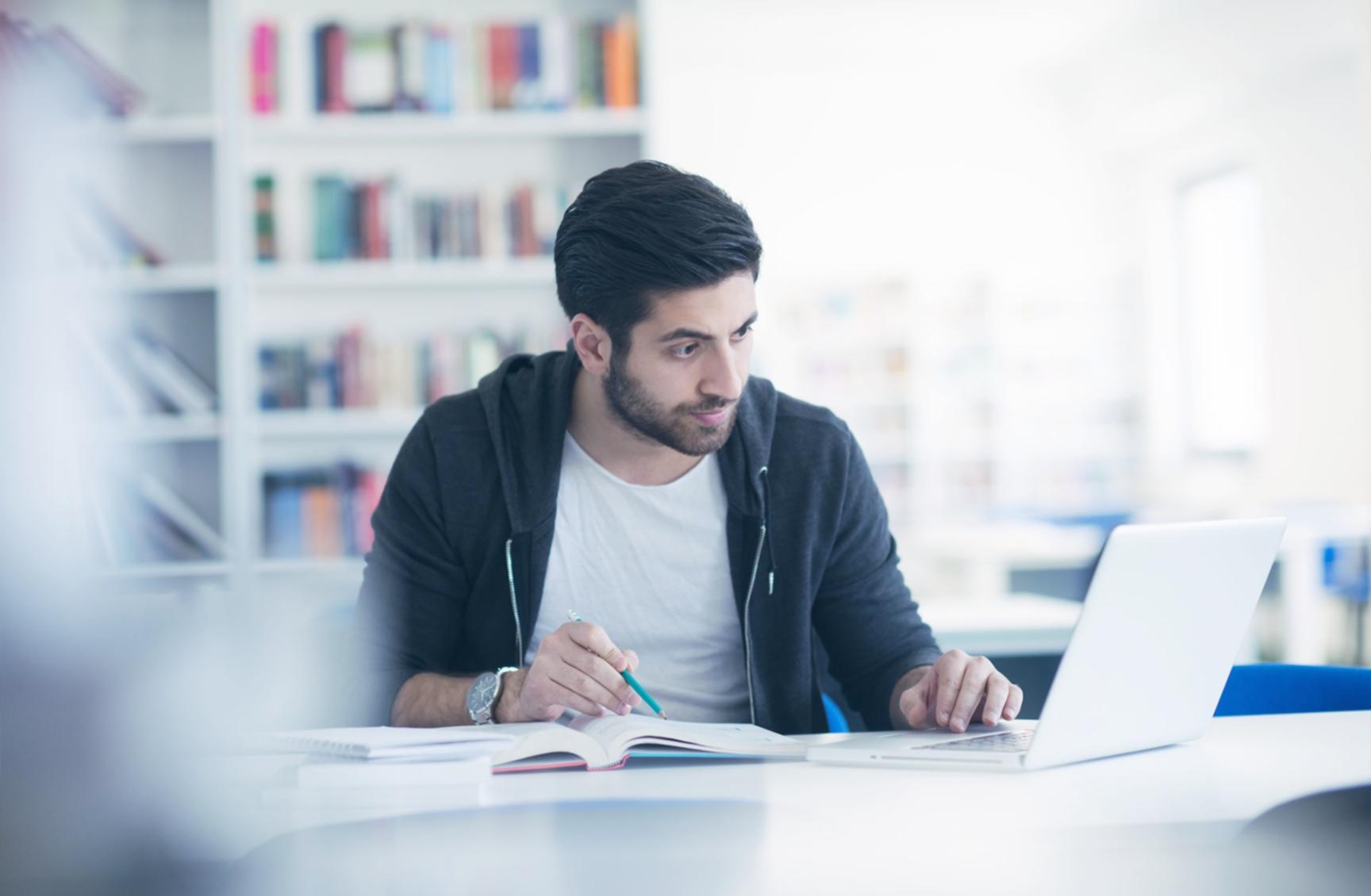 Student reviewing budget spreadsheet on laptop while studying remotely at home desk